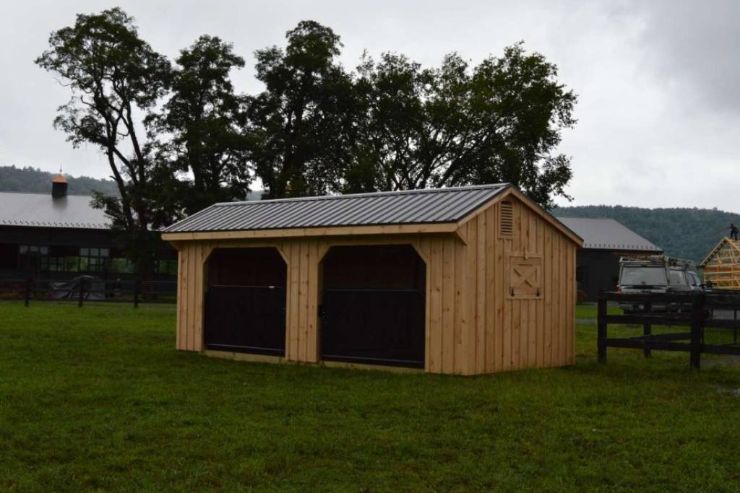 unpainted loafing barn next to larger barn