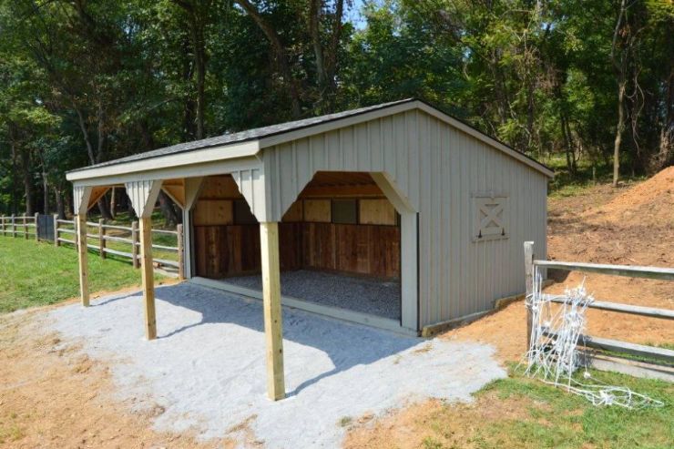 white wood loafing shed in front of trees