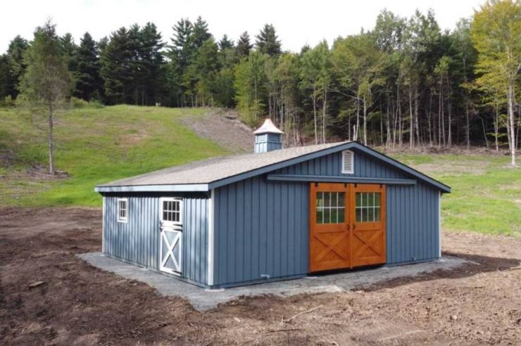 wood horse stall modular with surrounding dirt and forest in the background