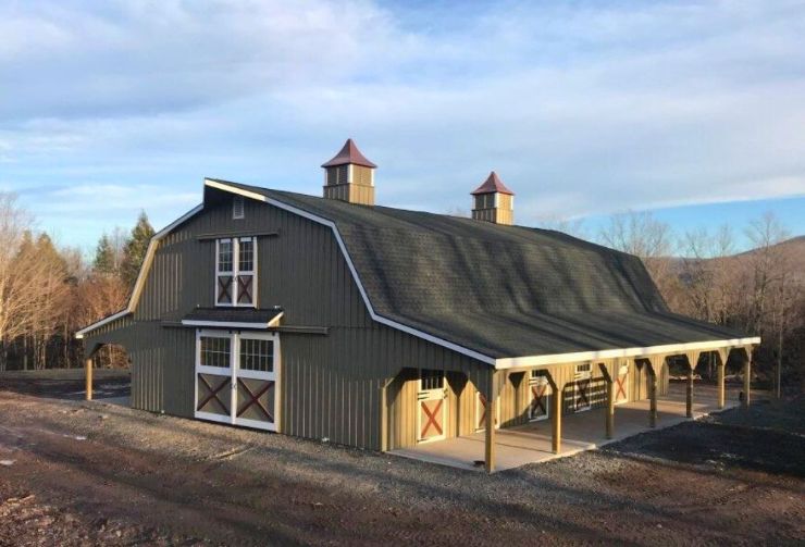 large horse barn in the gambrel style with two cupolas and a lean to on each side