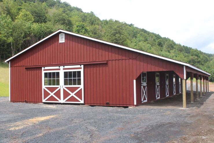 A red barn with low-pitch barn roof style located in a rural area