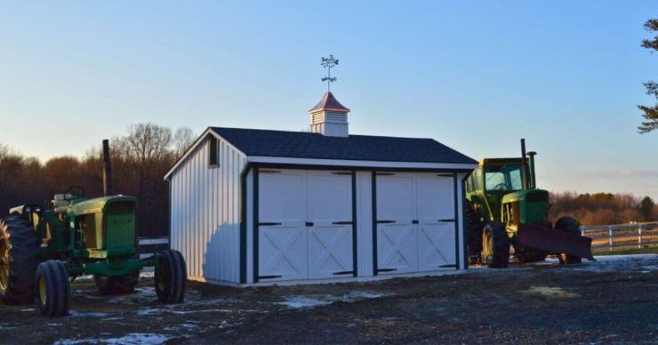 white double door backyard workshop shed with tractors on either side