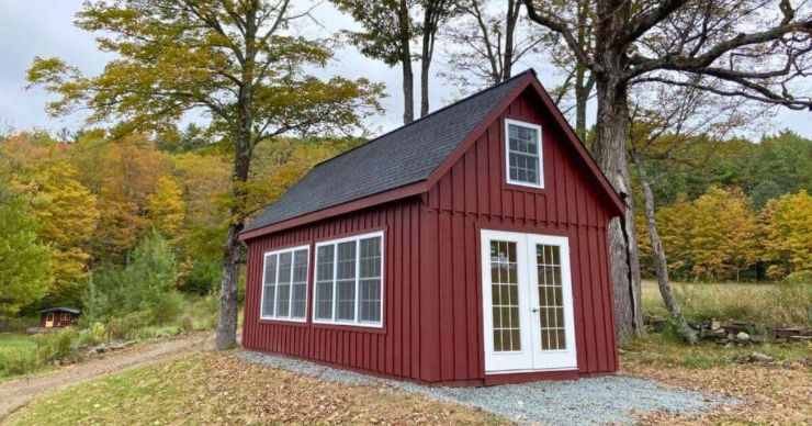 red backyard workshop shed with white french doors with a fall backdrop