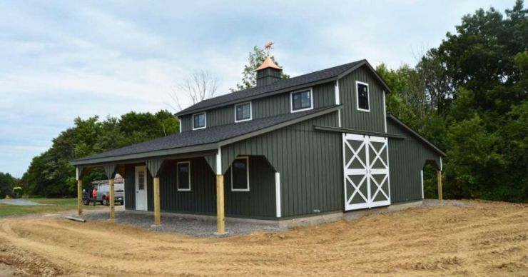 green monitor barn with double lean to and white trim on a dirt ground